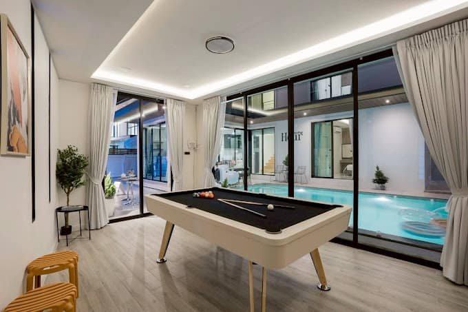 Living room with a pool table and glass doors onto the pool at Aqua Pool Villas