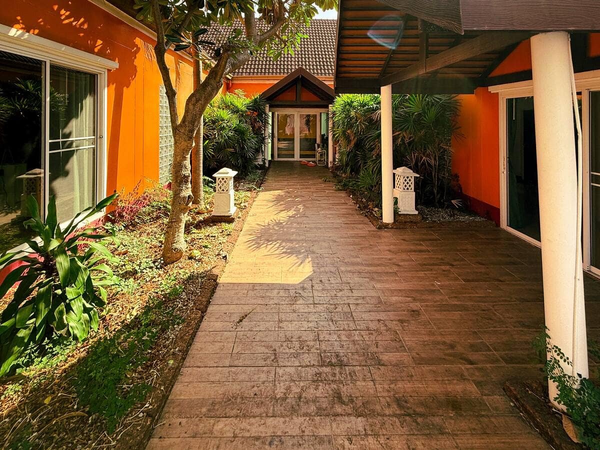 Garden walkway between orange villa walls at Magnitude Pool Villas, Pattaya